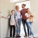 Family Opening Door And Walking In Empty Lounge Of New Home